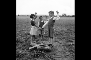 Three children standing by wooden logs making a vow.