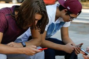 трое подростков с мобильными телефонами
