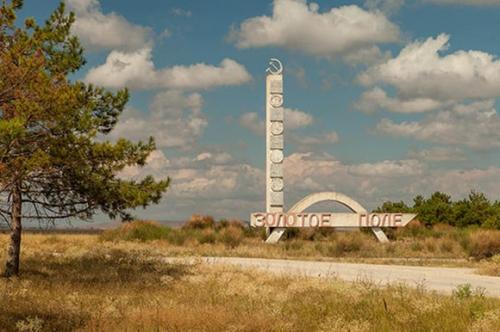 Russisches Ortsschild von Zolotoe Pole, mit Hammer und Sichel auf Betonsockel