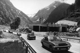 Noch im Bau befindliches Tunnelportal in alpiner Umgebung, links ein grosser Felsbrocken